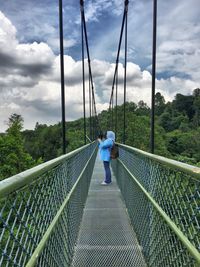 Woman photographing while standing on bridge at macritchie reservoir park