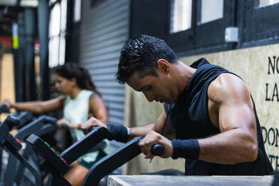 Group of sportive hispanic people in activewear standing in light spacious modern gym with various professional equipment during training together