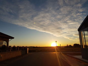 Road by city against sky during sunset