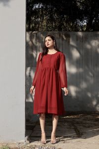 Portrait of young woman standing against wall