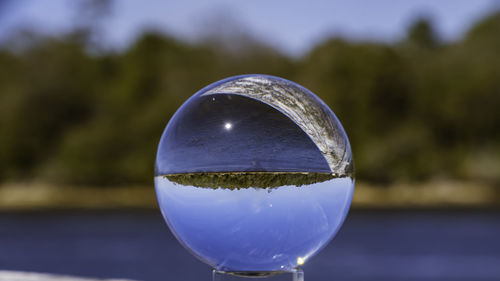 Close-up of crystal ball against sky