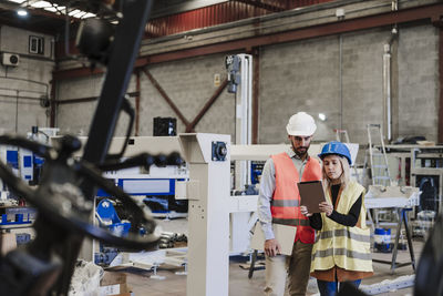 Engineer with colleague using tablet computer at industry