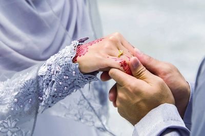 Cropped image of groom holding bride hand