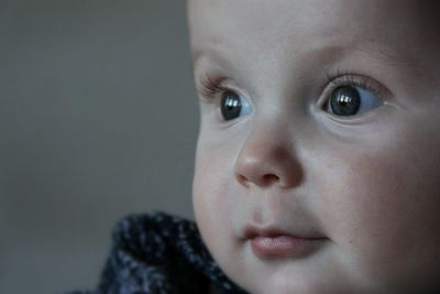 Close-up of cute baby boy looking away against wall