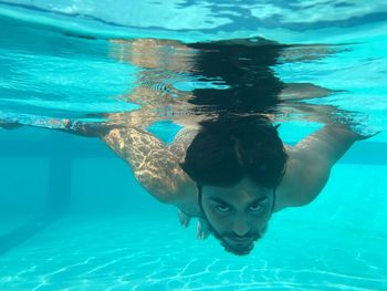 Portrait of young man swimming underwater in pool