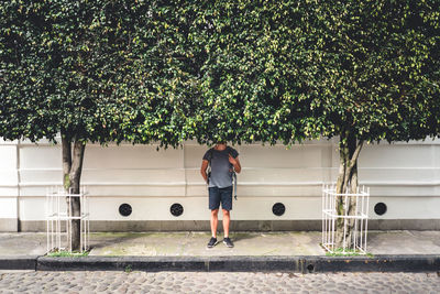 Rear view of woman standing on footpath against trees