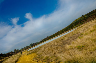 Scenic view of road amidst field against blue sky