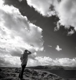 Rear view of man standing on landscape against cloudy sky