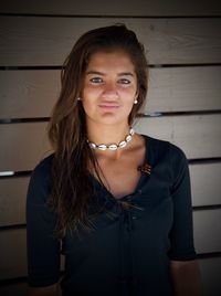 Portrait of beautiful young woman standing against wall