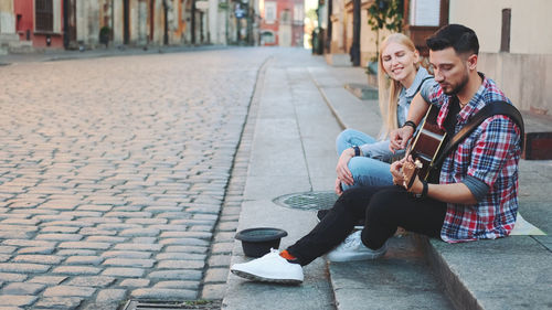 Young couple sitting on mobile phone in city