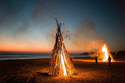 Bonfire on beach against sky at night