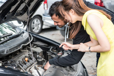 Man and woman looking at car engine