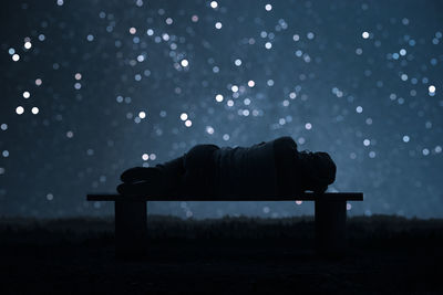 Side view of silhouette man on bench at field