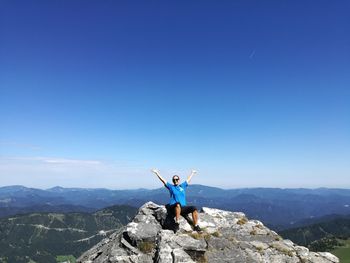 Man standing on mountain against blue sky