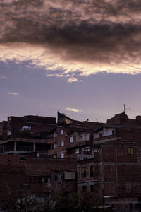 Exterior of houses in town against sky at sunset