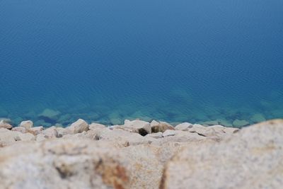 Close-up of rocks on beach against blue sky