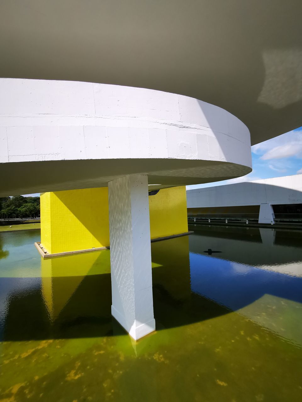 CLOSE-UP OF YELLOW UMBRELLA ON TABLE BY LAKE