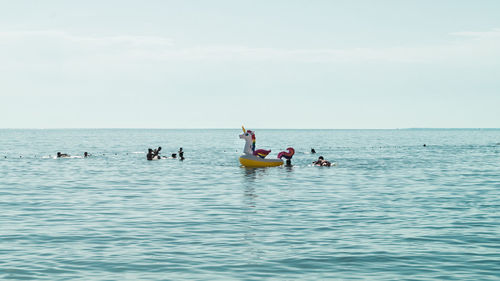 People swimming in sea against sky