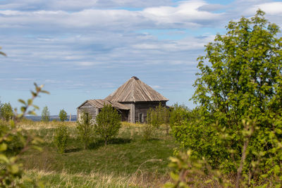 Old church on field by trees against sky