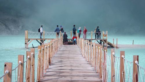 People on pier over lake during foggy weather