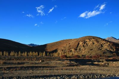 Scenic view of field and mountains against blue sky