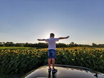 Rear view of person standing on field against sky