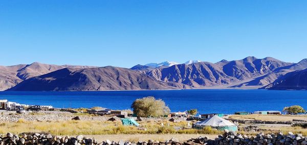 Scenic view of sea and mountains against clear blue sky