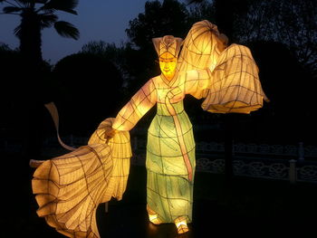 Low angle view of yellow statue against sky at night