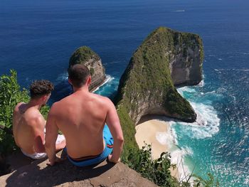 Rear view of shirtless man looking at sea