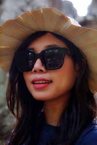 Close-up portrait of woman wearing sunglasses and hat