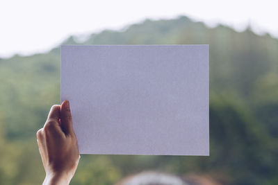 Close-up of hand holding paper against blurred background