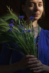 Portrait of woman with purple flowers against blue wall