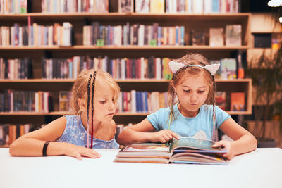 Two elementary schoolgirls doing homework in school library. students learning from books