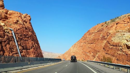 Road leading towards mountain against clear sky