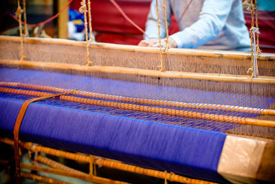 Midsection of man working with loom in workshop