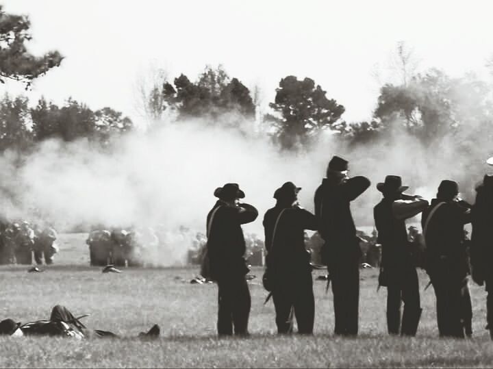 GROUP OF PEOPLE ON FIELD AGAINST TREES