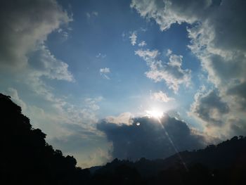 Low angle view of sunlight streaming through clouds