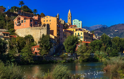 Buildings by lake against sky