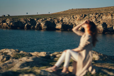 People on rock by sea against sky