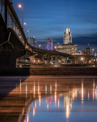 Illuminated bridge over river in city at night