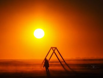 Silhouette man against sea during sunset