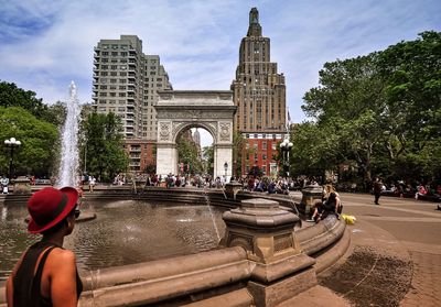 Tourists on city street against cloudy sky