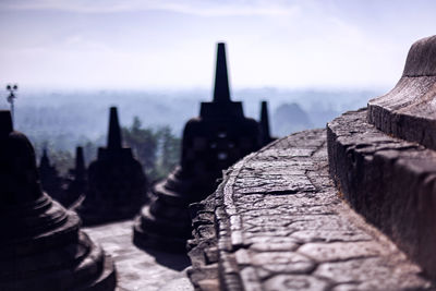 Low angle view of man standing on retaining wall against sky