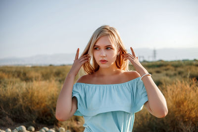 Teenage girl wearing dress standing on land against sky