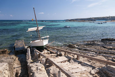 Small fishing boat on the rails on the rocky coast. boat on the wooden rails of formentera.