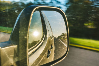 Reflection in side-view mirror of car on road