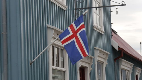 Low angle view of icelandish flag against  wooden blue buildings