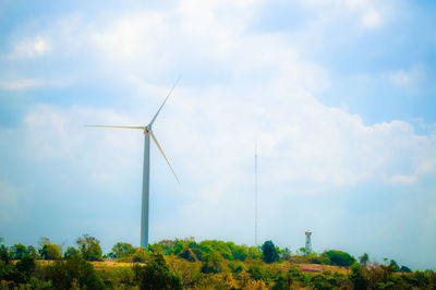 Low angle view of wind turbines on landscape against sky