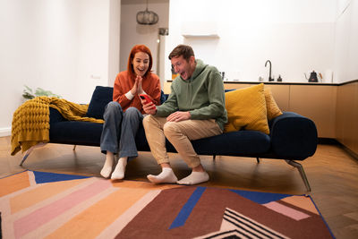 Young woman using laptop while sitting on sofa at home