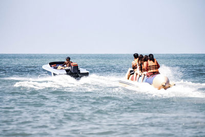 People on boat in sea against clear sky